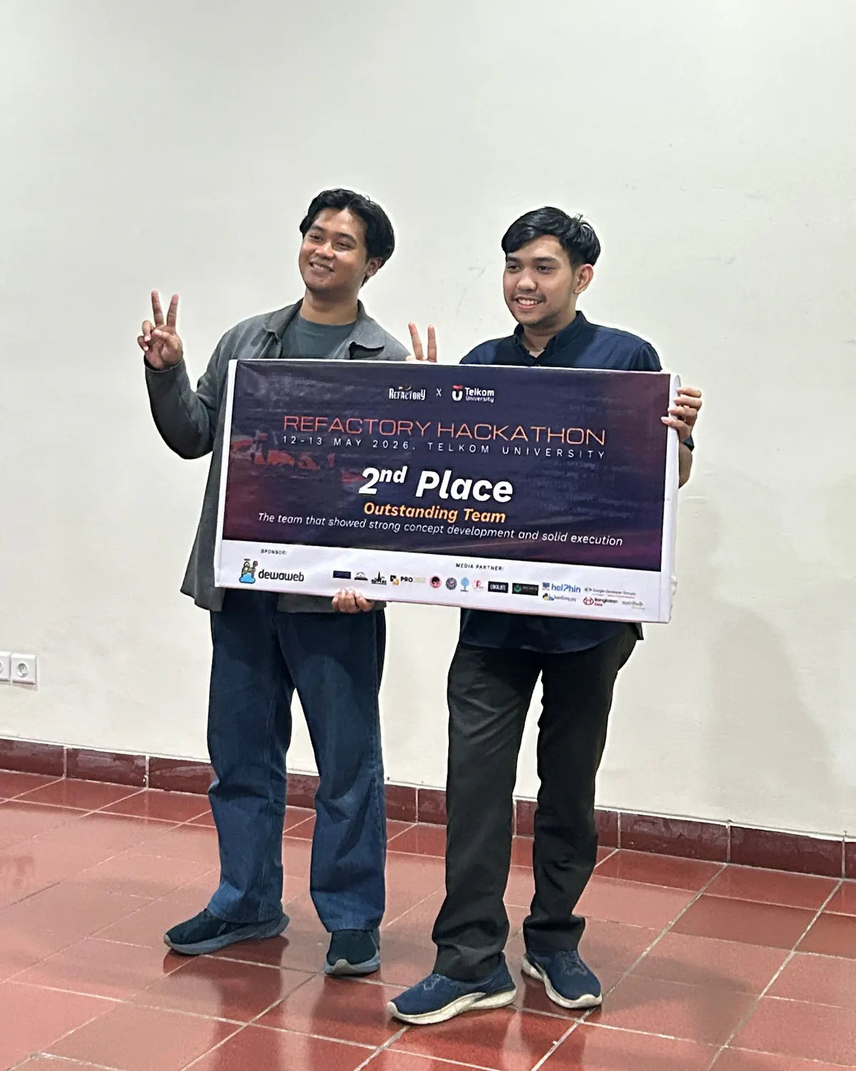 Wildan and a teammate hold a Refactory Hackathon placard reading 2nd Place, Outstanding Team.